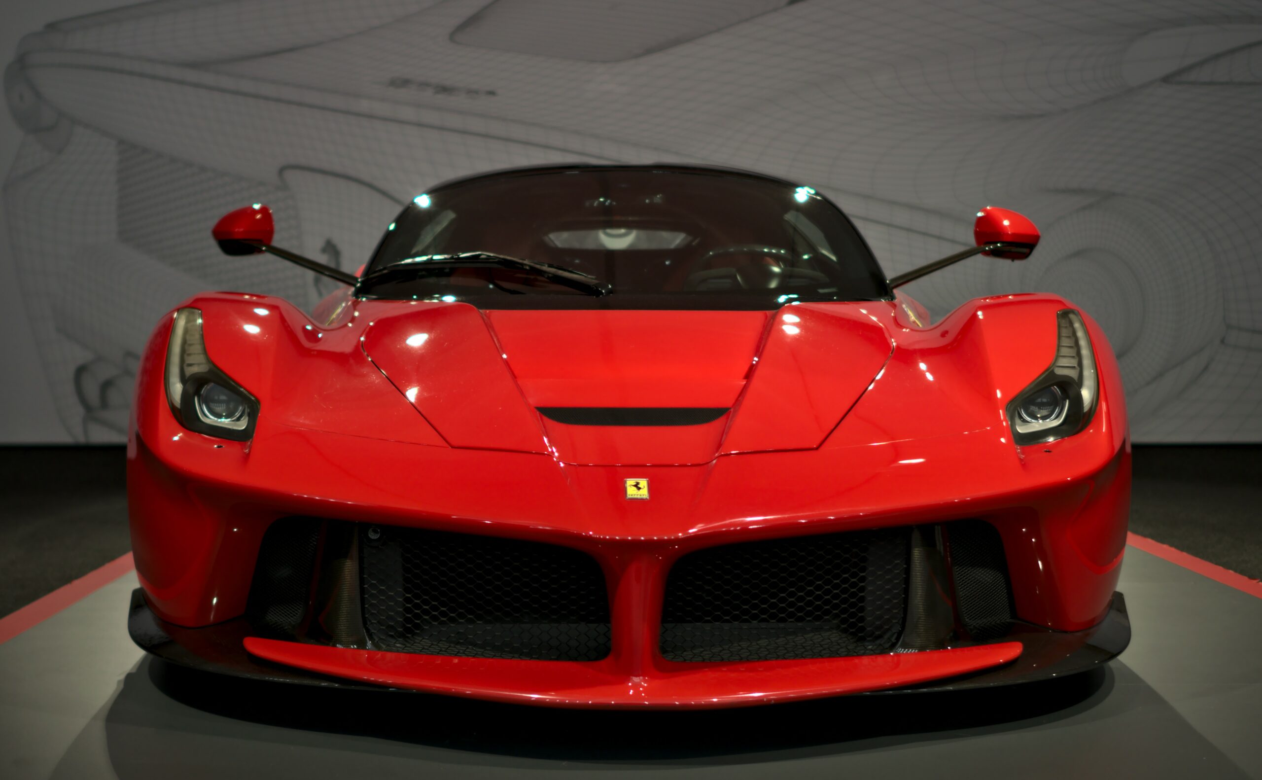 Front view of a red Ferrari LaFerrari hypercar on display, highlighting its aerodynamic design, carbon fiber front splitter, and aggressive styling.