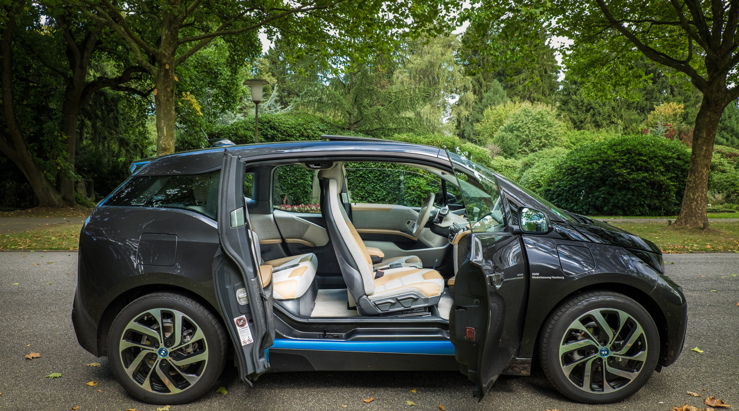 Side view of a BMW i3 electric car with its front and rear doors open, showing the spacious interior and rear-hinged coach doors design.