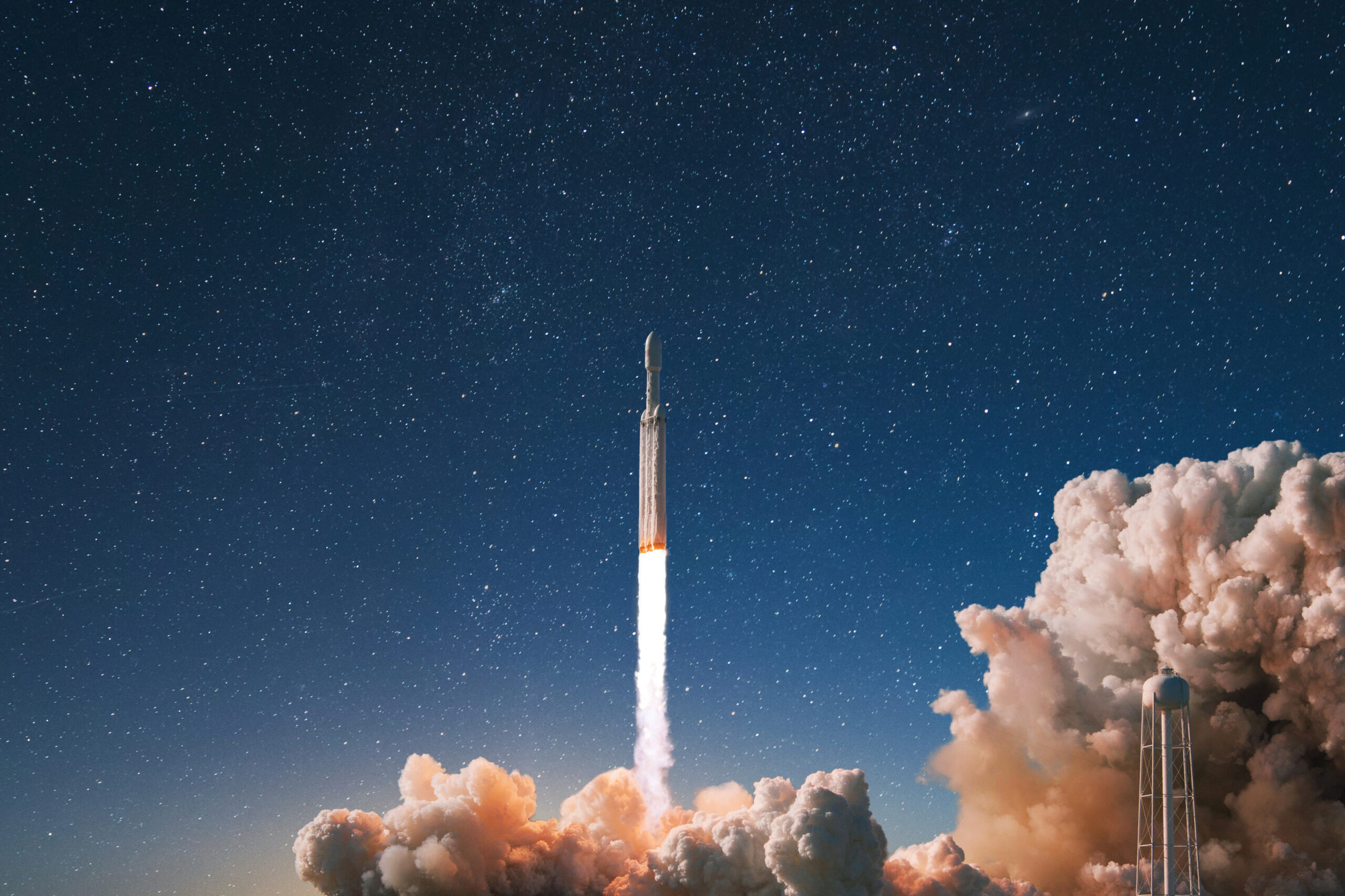 Rocket launching into space at night, leaving a bright exhaust trail and surrounded by smoke clouds under a starry sky.