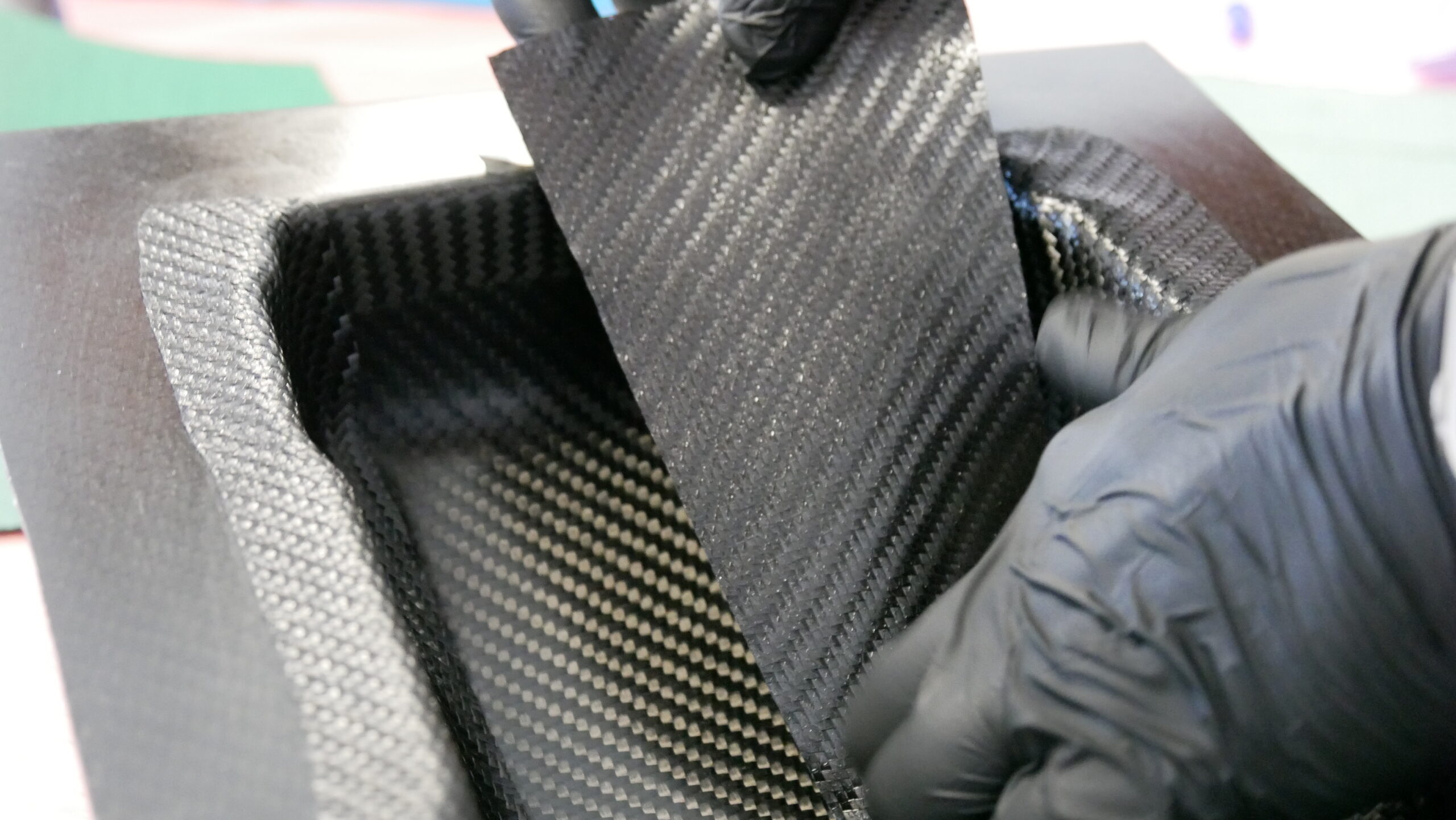 Technician placing carbon fiber prepreg into a mold during composite lay-up process